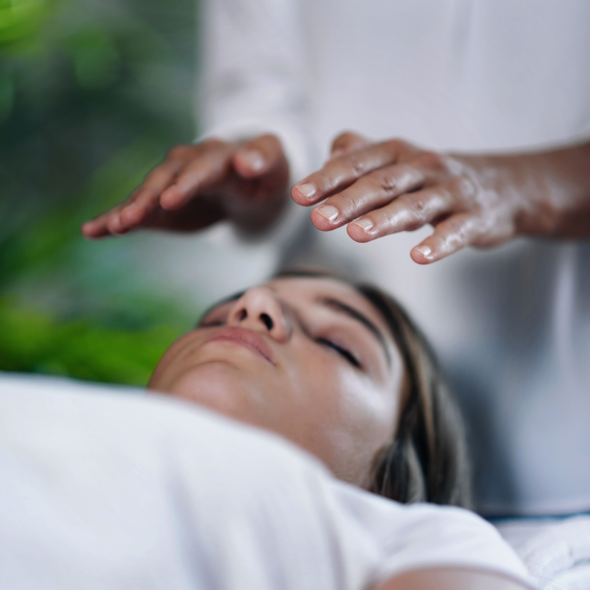 Midsection Of Therapist Giving Reiki Treatment To Teenage Girl On Face At Spa Midsection Of Therapist Giving Reiki Treatment To Teenage Girl On Face At Spa